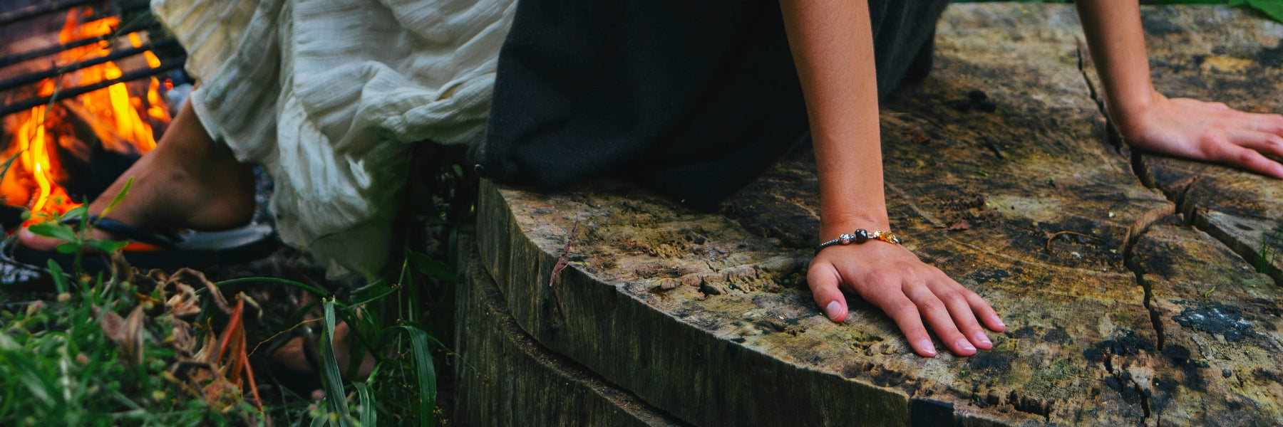 Model wearing a Phoenix Feather Bracelet while sitting next to a bunfire